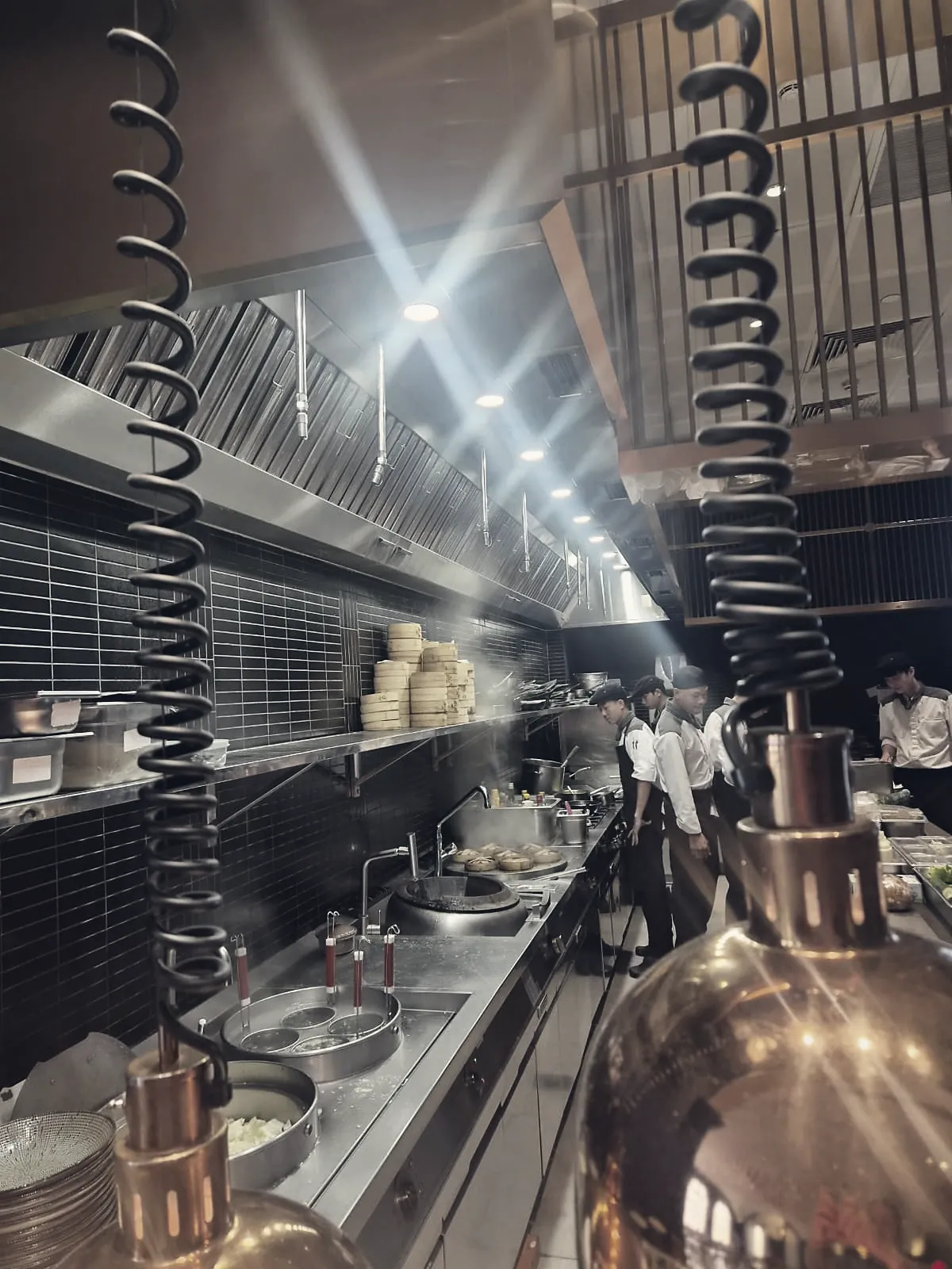 Open restaurant kitchen with a long hood over the wok line
